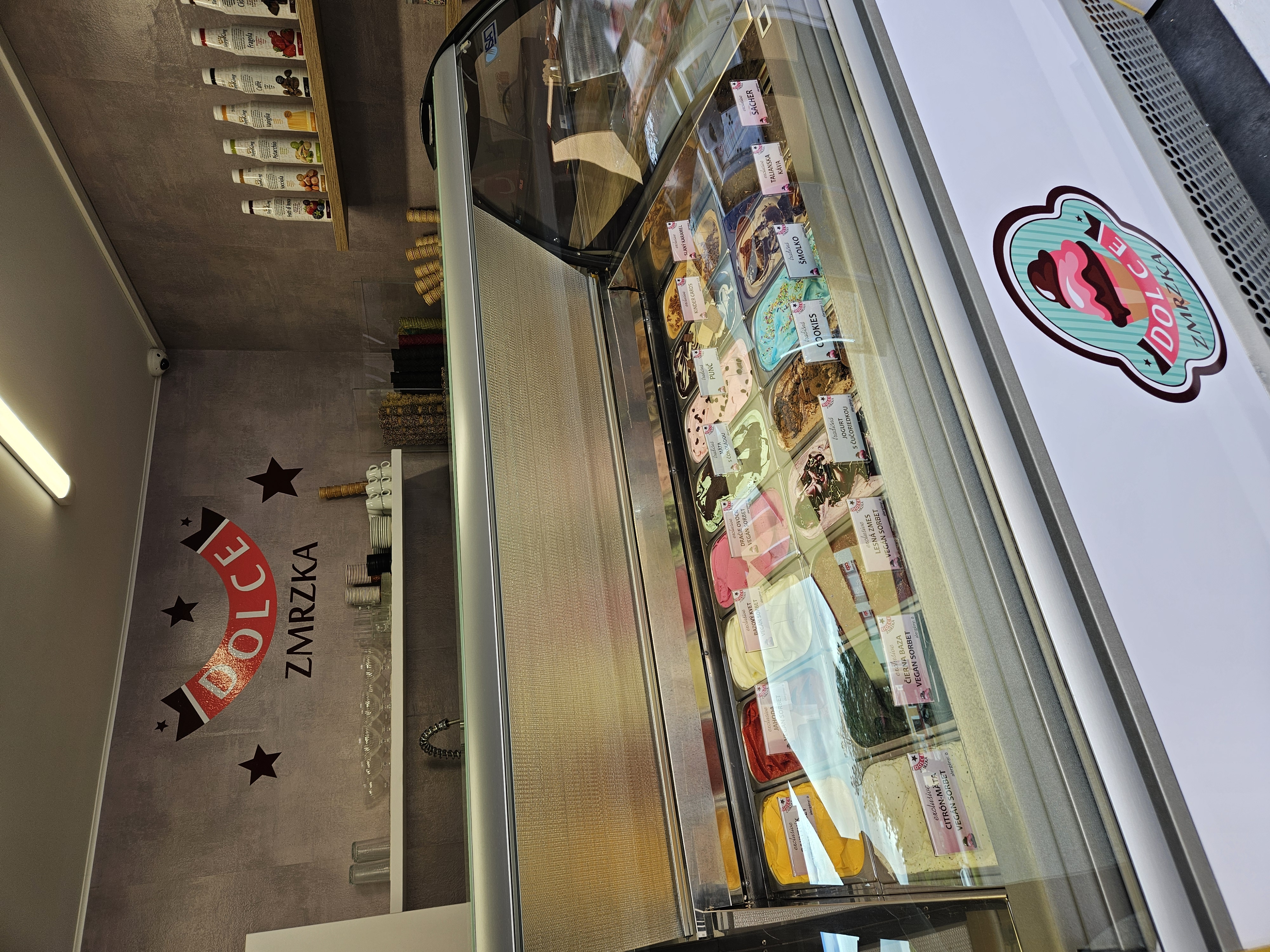 Interiér prevádzky DOLCE Zmrzka Blatnica s gelato vaničkami a logom na stene